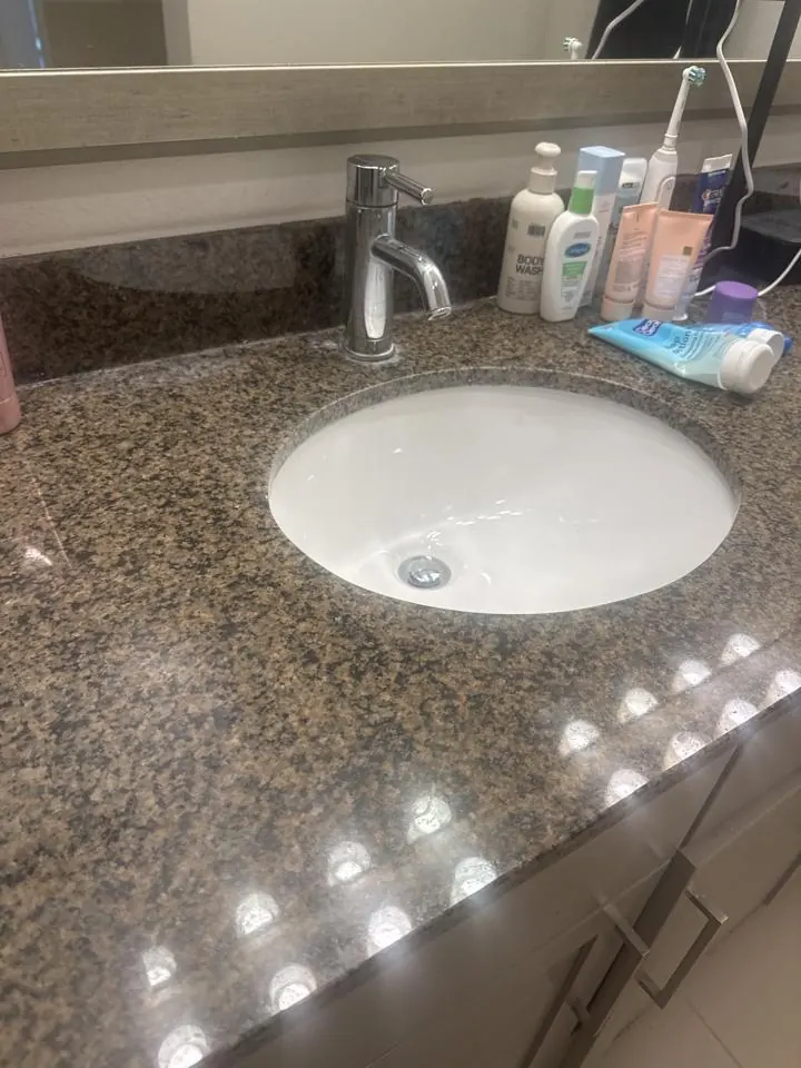 Round white bathroom sink set in a granite vanity top